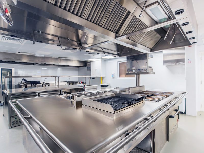 Commercial kitchen cooking line under a stainless steel exhaust hood